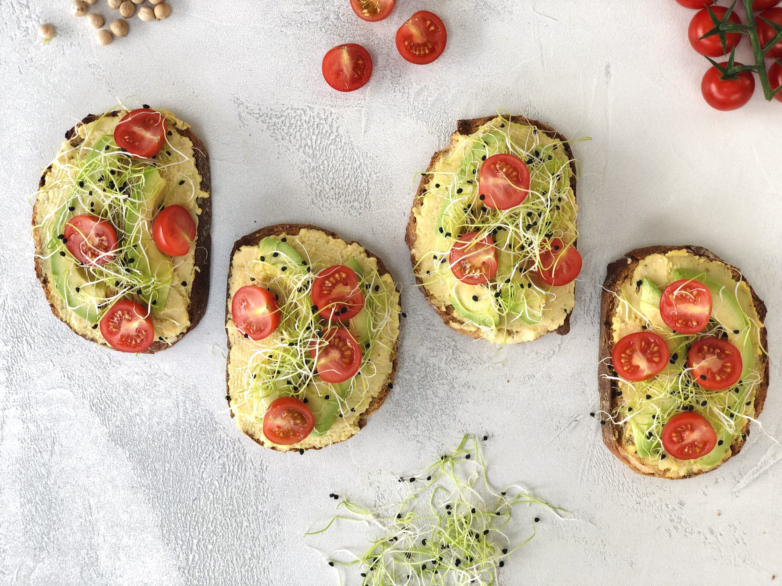 leckerster veganer Apero-Snack: Hummus Brötchen mit Avocado, Zwiebelsprossen und Cherrytomaten