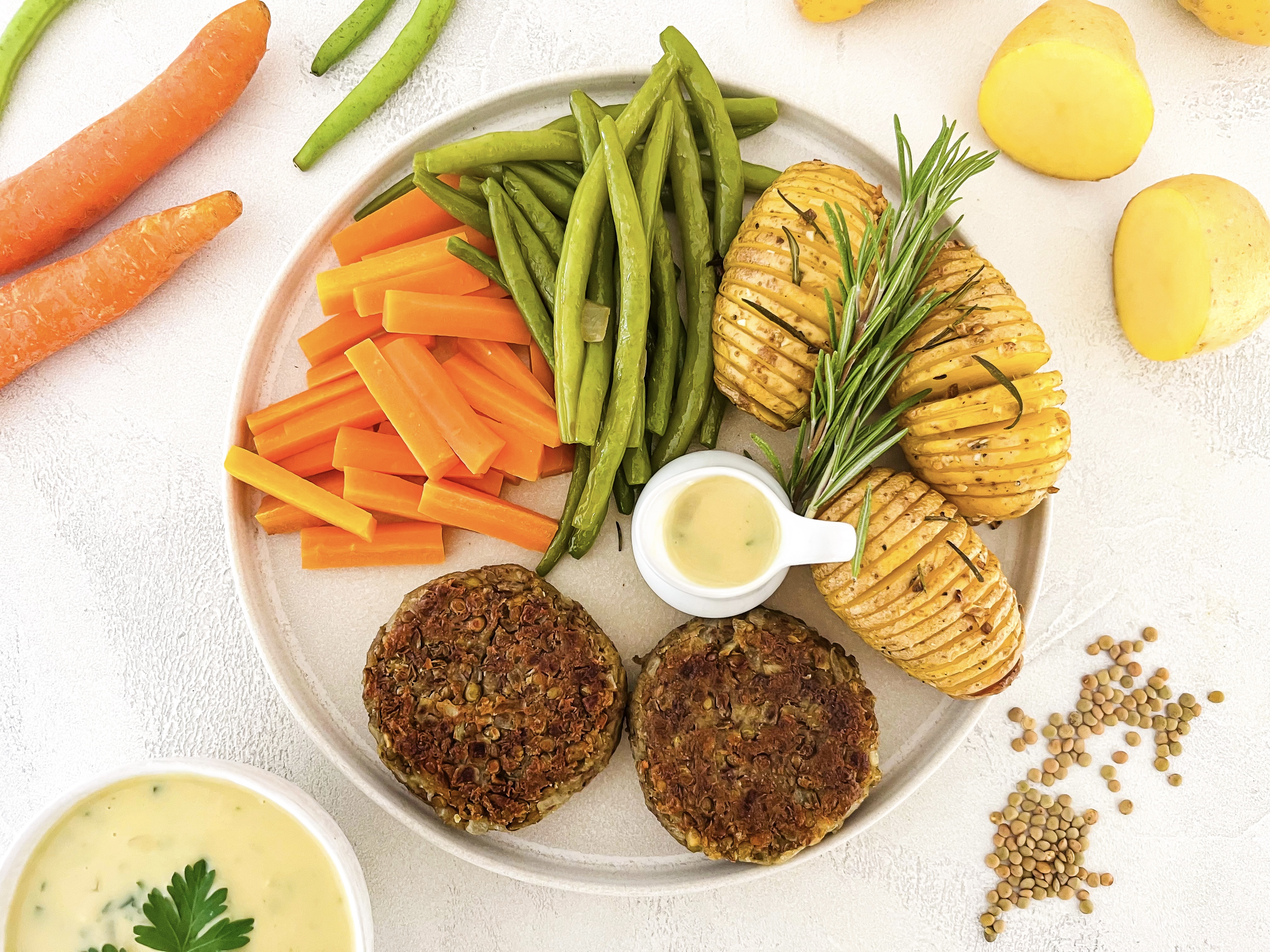 Ausgewogener Teller: Linsen Patty mit Fächerkartoffeln, Gemüse und Kräuter-Rahmsauce (vegan)